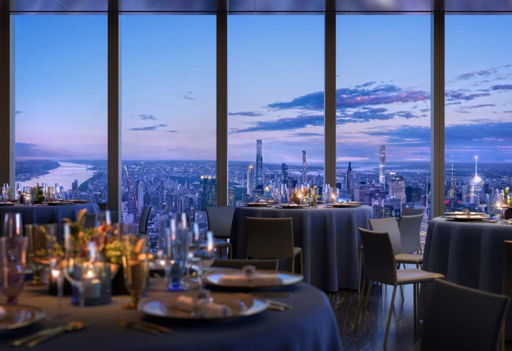 Elegant dining room with candlelit tables and plush seating, set against a panoramic view of a city skyline at dusk. Tall windows offer a breathtaking vista of skyscrapers and a river under a colorful evening sky.